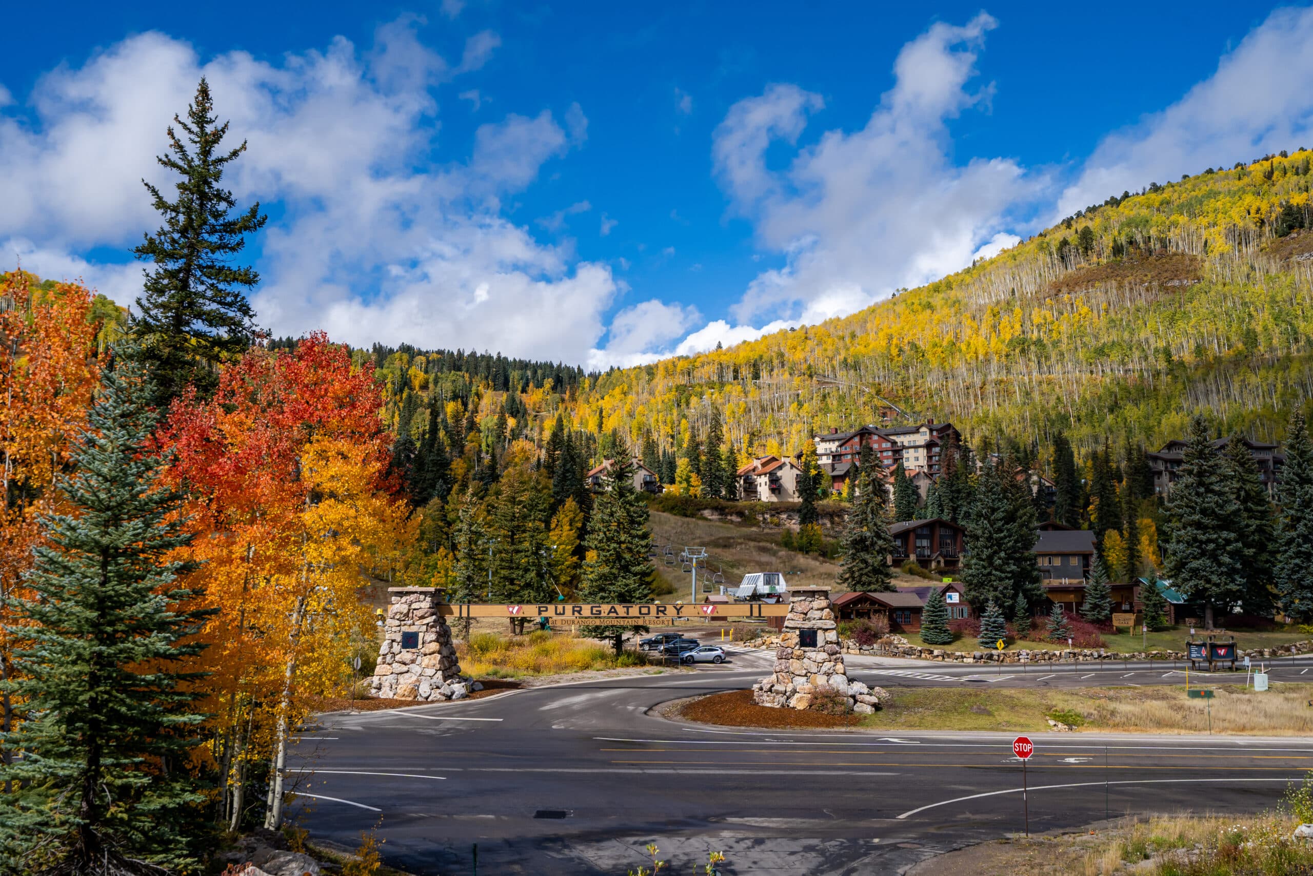 a sign for the Purgatory Resort with fall foliage in the background
